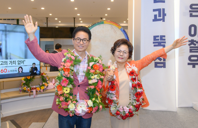 6·3 지방선거에서 3선에 성공한 이철우 경북도지사 당선인이 배우자와 함께 축하 꽃다발을 목에 걸고 인사하고 있다. 연합뉴스