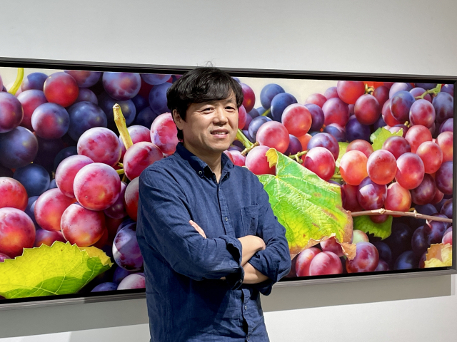 김대연 작가가 자신의 사진 앞에서 포즈를 취하고 있다. 이연정 기자