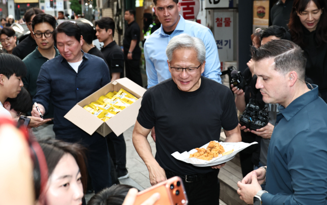 젠슨 황 엔비디아 최고경영자(CEO)와 최태원 SK 회장이 7일 서울 강남구 깐부치킨 삼성점에서 치맥 회동을 하던 중 과자와 치킨을 나눠주고 있다. 연합뉴스