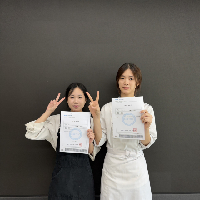 성주군 명인고 3학년 제과제빵과 도티티냐(오른쪽) 학생과 같은 학년 외식조리과 딘티뉴퀸 학생이 각각 제과기능사와 양식조리기능사 시험 합격 확인서를 보이고 있다. 명인고 제공