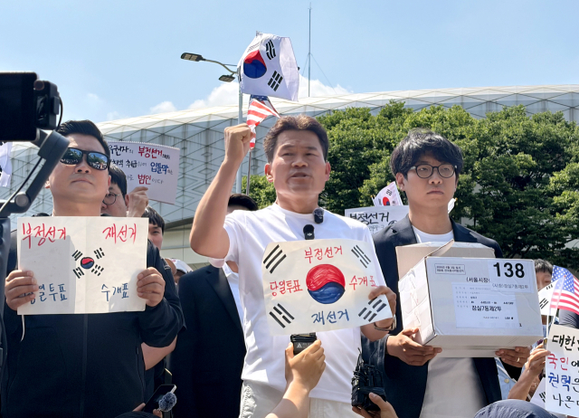 전 한국사 강사 전한길씨와 전씨의 지지자들이 12일 개표소 봉쇄 시위 현장인 서울 송파구 SK핸드볼경기장 앞에서 잠실7동 제2투표소에 보관돼 있다 사라진 투표용지 보관상자 중 1개를 제보를 통해 확보했다고 주장하며 상자를 공개하고 있다. 앞서 전씨가 설립한 언론사 원웨이뉴스는 이날 보도자료를 내고 