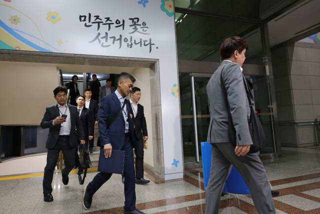 6·3 전국동시지방선거 투표용지 부족 사태를 들여다보고 있는 검경 합동수사본부 관계자들이 11일 경기도 과천 중앙선거관리위원회에서 압수수색을 마친 뒤 압수품을 들고 건물을 나서고 있다. 연합뉴스