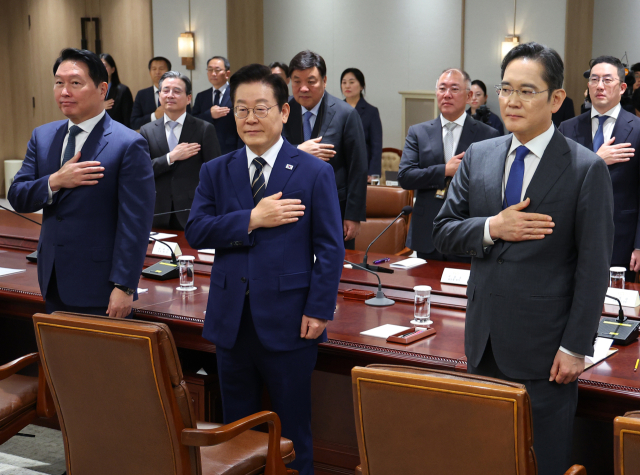 이재명(가운데) 대통령이 이재용(오른쪽) 삼성전자 회장과 최태원 SK그룹 회장 등 재계 인사들과 함께 지난해 11월 한미 관세협상 후속 민관 합동회의에서 국기에 경례하는 모습. 연합뉴스