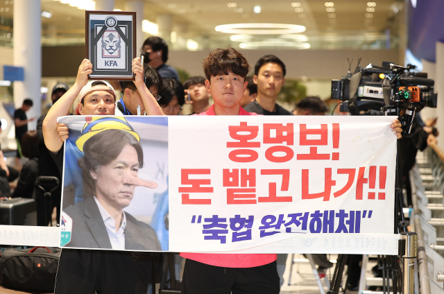 2026 북중미 월드컵 32강 진출에 실패해 한국 축구대표팀 지휘봉을 내려놓은 홍명보 전 감독이 입국하는 30일, 인천국제공항 제2여객터미널을 찾은 팬들이 항의 현수막을 들어 올리고 있다. 연합뉴스