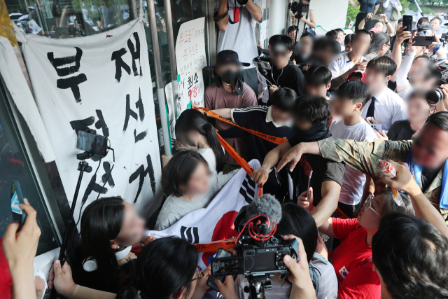 6·3지방선거 투표용지 부족 사태로 촉발된 잠실 개표소 봉쇄 시위가 12일째 이어진 16일 서울 송파구 올림픽공원 핸드볼경기장 개표소 앞에서 시민들이 국민의힘과 대한체육회 관계자들의 진입을 봉쇄하기 위해 문을 잡고 있다. 연합뉴스