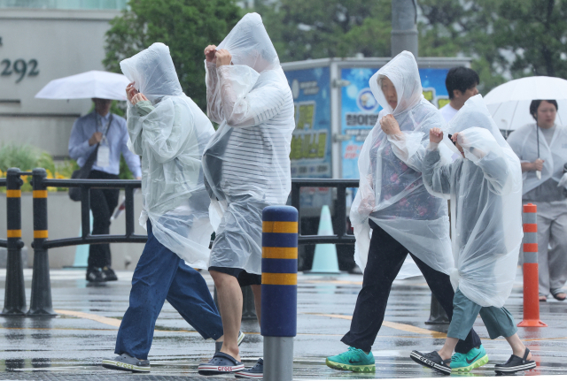 장마가 시작된 1일 부산 해운대구 구남로에서 비옷을 입은 관광객들이 발걸음을 옮기고 있다. 연합뉴스