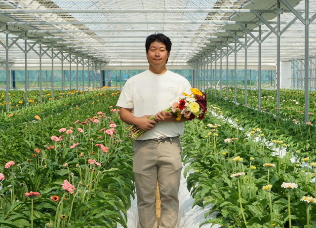 박현민 씨가 하우스에서 재배한 미니 거베라를 들고 서 있다. 본인 제공
