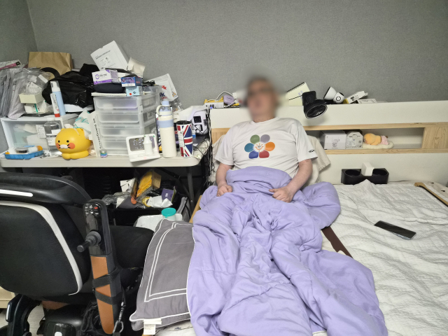 두 다리와 한쪽 눈을 잃은 박상철(가명) 씨가 침대에 누워 힘겨운 하루를 버텨내고 있다. 방 한편에 덩그러니 놓인 무거운 전동 휠체어와 식탁 위 수북한 약봉지가 전신마비의 공포와 싸우는 그의 막막한 처지를 고스란히 보여준다. 배형욱 기자