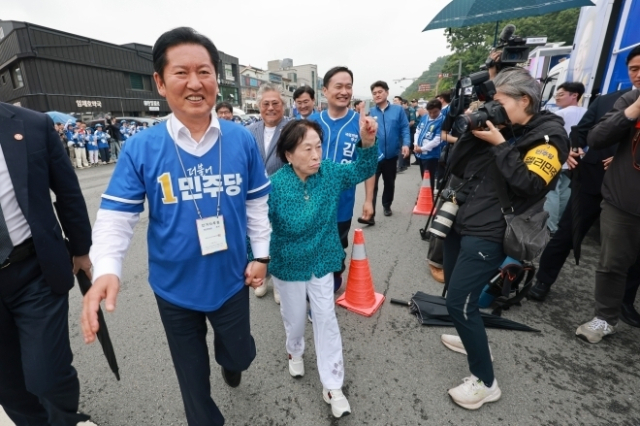 정청래 더불어민주당 총괄상임선거대책위원장이 지난 5월 충남 공주산성시장에서 민주당 박수현 충남지사 후보와 김영빈 충남 공주부여청양 국회의원 보궐선거 후보 지원 유세를 하는 가운데 배우 전원주의 손을 잡고 이동하고 있다. 연합뉴스