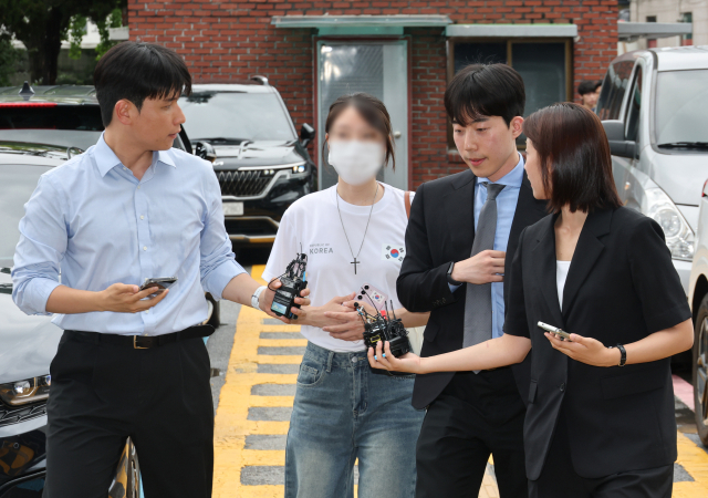 6·3 지방선거 개표소로 사용된 올림픽공원 핸드볼경기장 문 앞에서 체육단체 직원들의 장내 사무실 진입을 막아 업무 방해 혐의를 받는 30대 여성이 10일 서울 송파경찰서에서 조사받기 위해 출석하고 있다. 연합뉴스