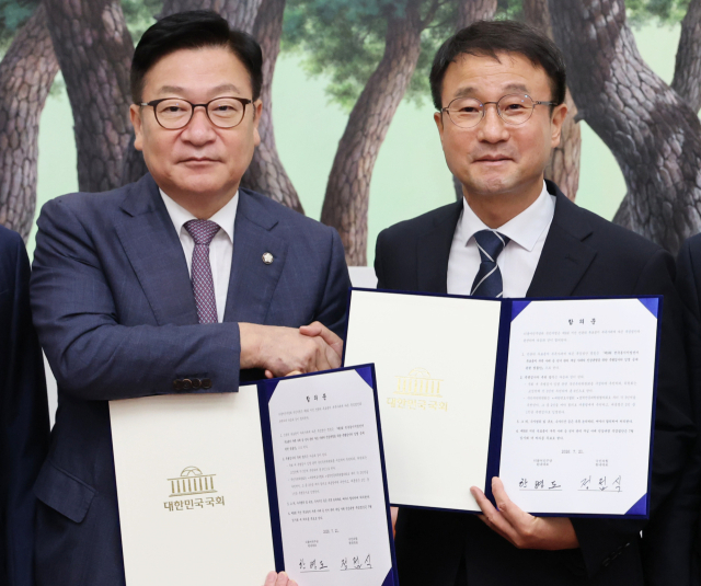 더불어민주당 한병도 대표 직무대행 겸 원내대표(오른쪽)와 국민의힘 정점식 원내대표가 21일 국회 운영위원장실에서 선관위 투표용지 부족 사태에 따른 특검법안 합의문에 서명한 뒤 악수하며 기념 촬영을 하고 있다. 연합뉴스