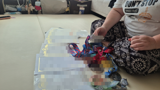 가정폭력 피해 트라우마에 정상적인 사회생활이 어려운 정선아(가명) 씨가 자신의 거주지에서 아들 성민(가명) 군의 태권도 관련 상장과 메달을 들여다보고 있다. 김지수 기자