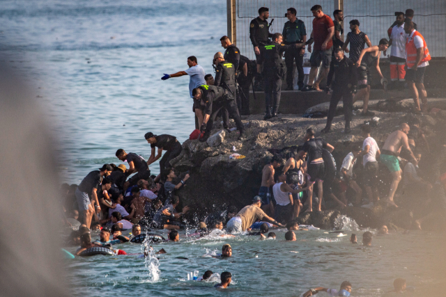30일(현지시간) 모로코 사람들이 스페인령 세우타(Ceuta)로 넘어가기 위해 바다를 헤엄쳐 나가고 있는 모습. AP 연합뉴스