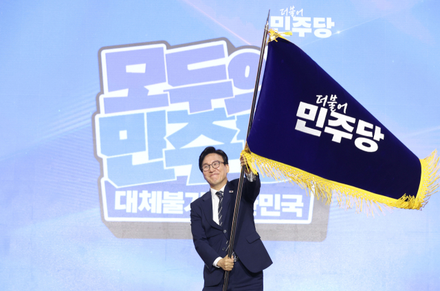 더불어민주당 김민석 신임 당 대표가 17일 대전 컨벤션센터에서 열린 제3회 더불어민주당 정기 전국당원대회에서 당 대표로 선출된 뒤 당기를 흔들어 보이고 있다. 연합뉴스
