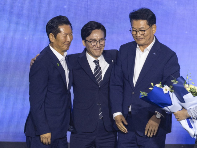 17일 대전 컨벤션센터에서 열린 제3회 더불어민주당 정기 전국당원대회에서 더불어민주당 신임 당 대표로 선출된 김민석 전 총리(가운데)가 당 대표직을 놓고 경쟁을 벌였던 정청래 전 대표(왼쪽)과 송영길 의원이 서로 포옹하며 축하와 위로를 하고 있다. 연합뉴스