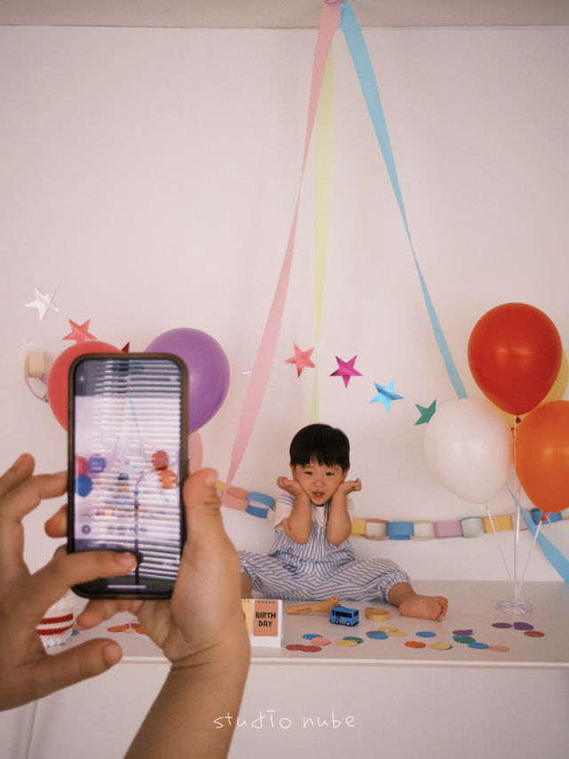 최근 키즈 생일 촬영은 아이에게 정해진 포즈를 요구하기보다 자유롭게 놀고 움직이는 순간을 자연스럽게 담는 방식으로 변화하고 있다. 사진은 생일 촬영 중인 아이의 모습을 부모가 휴대전화로 함께 기록하는 모습. 독자 제공