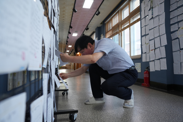 안동강남초등학교 황석수 교장이 교장실 앞에 마련된 게시대에 전교생이 필사한 종이를 직접 정리해 붙이고 있다. 김영진 기자