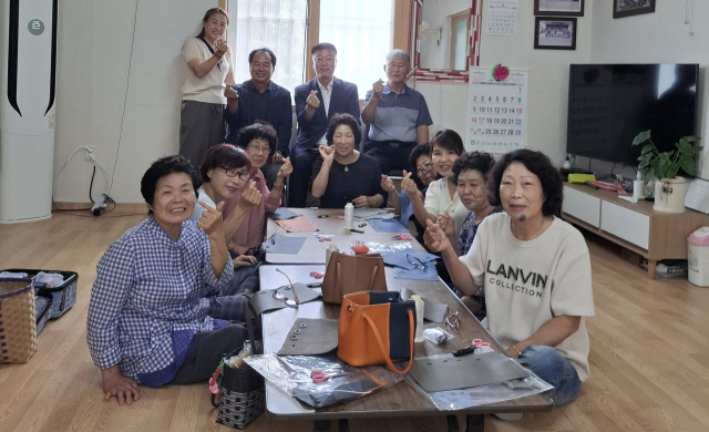 성주군 초전면 자양1리 어르신들이 자신들이 만든 가죽가방 등을 보여주고 있다. 뒷줄 왼쪽이 유미란 대표. 초전면 제공