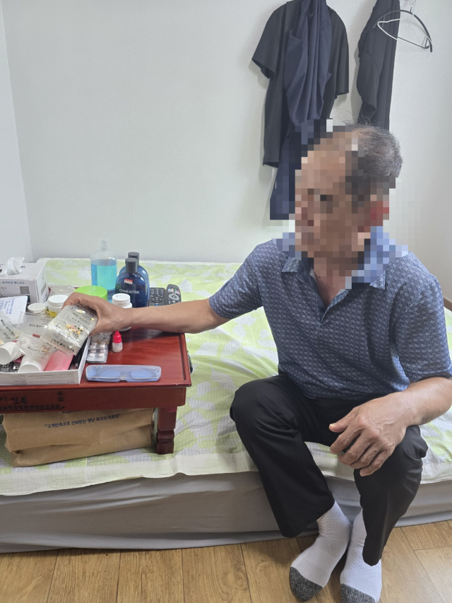 단칸방 침대에 걸터앉은 한형석(가명·63)씨가 매일 복용해야 하는 우울증 치료제 등 약을 살펴보고 있다. 옷가지 몇 벌만 걸린 작은 방에서 약에 의지해 하루하루를 버티고 있지만, 형석씨는 