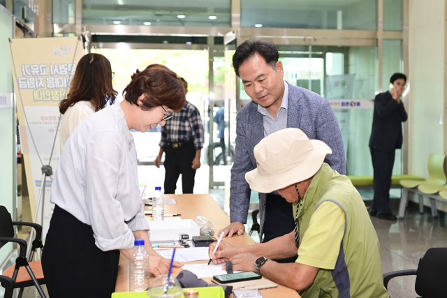 문경 고유가위기대응 지원금 신청 첫날인 지난 14일 김학홍 문경시장이 문경의 한 해정복지센터를 방문해 한 시민의 신청서류작성을 지켜보고 있다. 문경시 제공.
