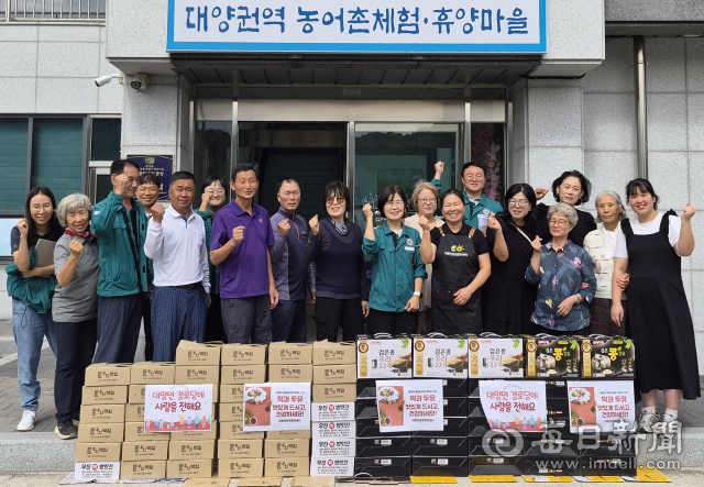 대양친환경영농조합법인 관계자들이 17일 대양친환경문화센터 앞에서 경로당에 전달할 떡과 두유를 앞에 두고 기념촬영을 하고 있다. 합천군 제공