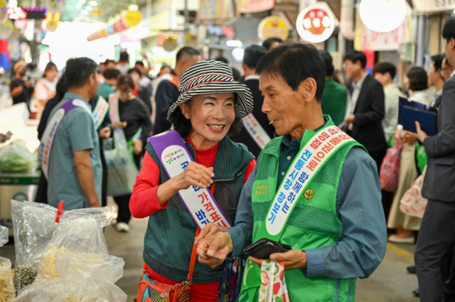 신영주번개시장 장보기 행사에 참여한 한 시민이 구입한 오징어 진미를 시식하며 환하게 웃고 있다. 마경대 기자