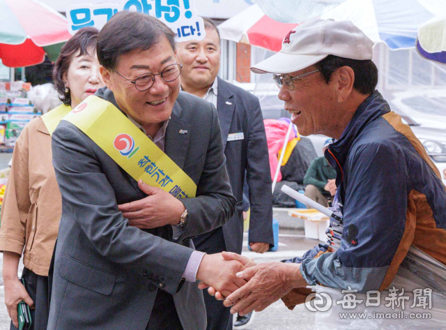 합천 왕후시장을 찾은 김윤철(왼쪽) 군수가 상인과 악수하며 인사를 나누고 있다. 합천군 제공