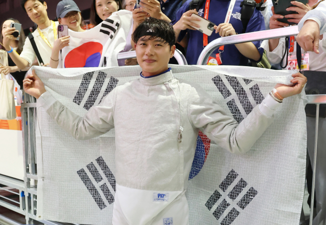 한국의 오상욱이 23일 일본 아이치현 도코나메 아이치 스카이 엑스포에서 열린 2026 아이치·나고야 아시안게임 남자 사브르 개인전 결승전에 출전, 중국의 선천펑을 상대로 승리하고 금메달을 차지한 뒤 태극기를 펼쳐 들고 있다. 연합뉴스