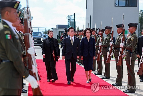 멕시코 국빈방문을 마친 이재명 대통령과 김혜경 여사가 26일(현지시간) 멕시코시티 펠리페 앙헬레스 국제공항에서 공군 1호기에 탑승하기 전 환송객에게 인사하고 있다. 연합뉴스
