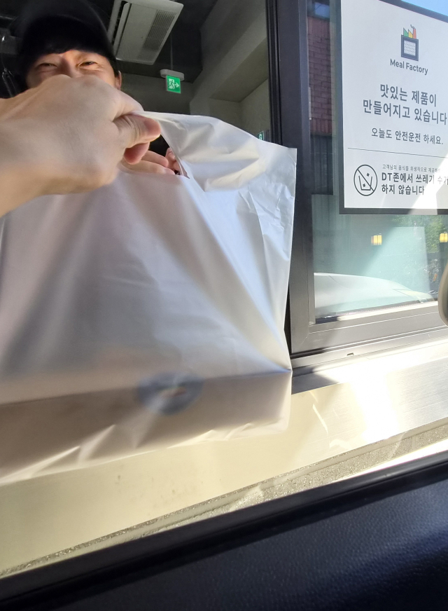 드라이브스루 매장에서 직원이 차량에 탑승한 고객에게 포장 음식을 건네고 있다. 임소현 기자