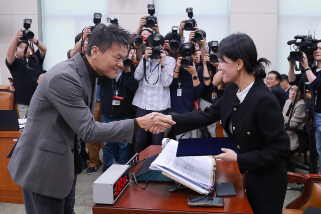 박진영 대중문화교류위원회 공동위원장이 7일 국회 문화체육관광위원회 국정감사에서 증인 선서문을 위원장인 더불어민주당 이재정 의원에게 제출한 뒤 악수하고 있다. 연합뉴스