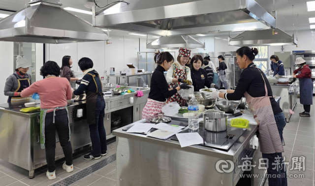 합천군 농업기술센터가 운영하는 김치 만들기 교육 실습 모습. 교육생들이 앞치마와 장갑을 착용하고 실습대에 둘러서서 김치 재료를 버무리고 있다. 합천군 제공
