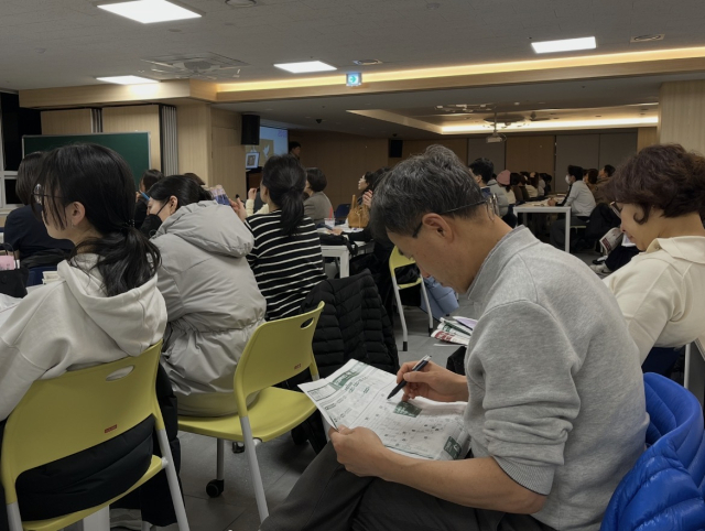 지난해 12월 대구 수성구 송원학원에서 열린 정시 설명회에서 한 아버지가 대학별 정시 배치표에 줄을 긋고 있다. 김영경 기자