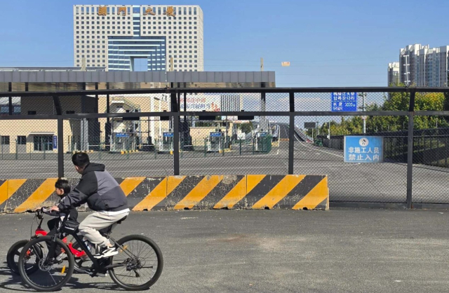 6일 오전 중국 랴오닝성 단둥 신압록강대교로 진입하는 중국 측 세관 건물 입구 앞으로 주민들이 탄 자전거가 달리고 있다. 이날 늦은 시간까지 이곳을 거쳐 대형 화물차나 화환 등이 이동하는 모습은 관찰되지 않았다. 연합뉴스