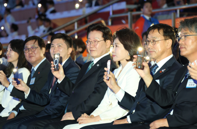 이재명 대통령이 16일 제주월드컵경기장에서 열린 제107회 전국체육대회 개회식에서 휴대폰 조명을 켜고 성화봉송을 보고 있다. 연합뉴스