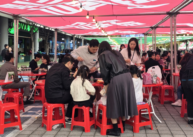 23일 오후, 대구 북구 DGB파크 일원에서 열린 떡볶이 축제. 사람들이 저마다 앉아서 떡볶이를 맛보고 있다. 김지효 기자.