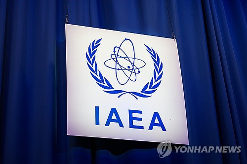 국제원자력기구(IAEA) 로고가 표시된 현판 앞에서 관계자들이 회의를 진행하고 있다. 연합뉴스